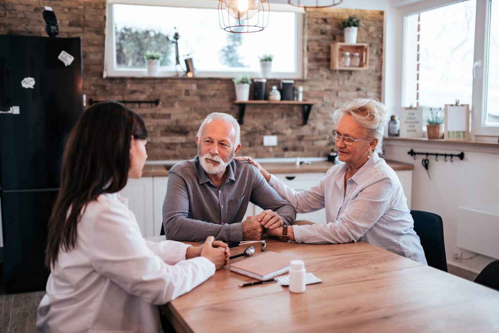 Senior couple talking to a doctor at home.